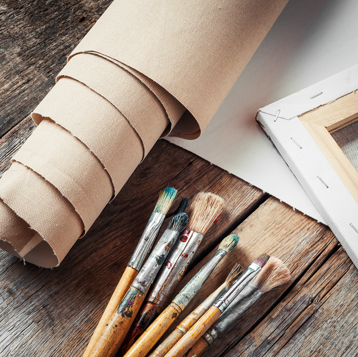 Studio Materials: Canvas and paintbrushes on wooden table. First steps of graphic design.